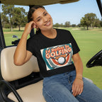 Woman wearing a black t-shirt with 'I'd Rather Be Golfing' design, sitting in golf cart.